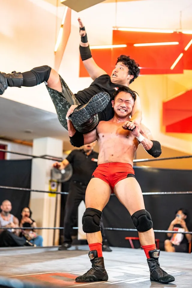 A wrestler carries his opponent on his shoulders